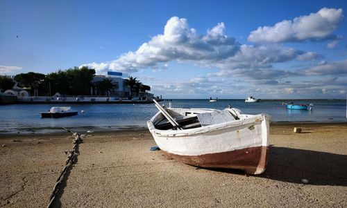 Boat moored on beach against sky