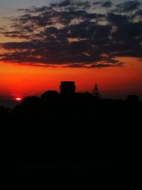 Silhouette trees against orange sky