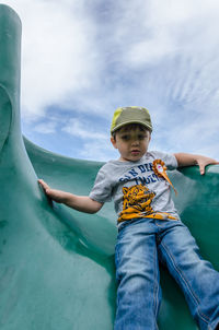 Low angle view of boy on slide against sky