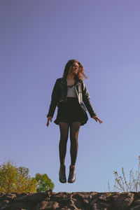 Low angle view of woman standing against clear sky