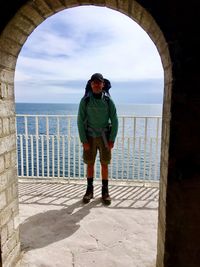 Full length of man standing against sea seen through arch