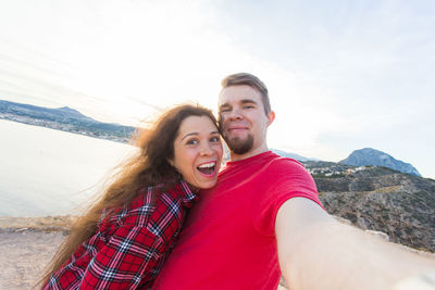 Portrait of smiling young couple against sky