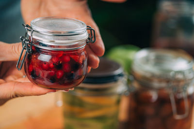 Woman holding jars with fermented fruits.