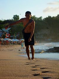 Full length of man standing on beach against sky