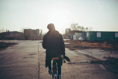 Rear view of man riding bicycle on city