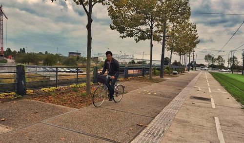 Man riding bicycle on bridge in city