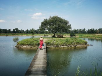 Rear view of woman walking on pier by lake