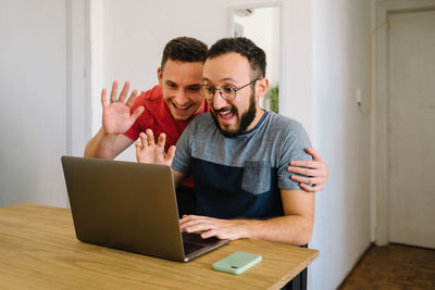 Two men saying hello and looking at a laptop.