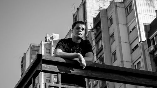 Low angle view of man standing by railing against building