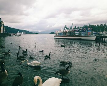 Boats in sea against cloudy sky