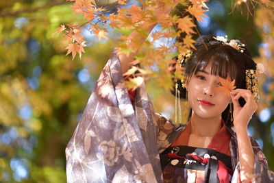 Portrait of young woman standing by plants