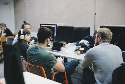 Computer programmers discussing at desk in office