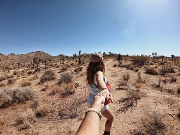 Cropped image of man holding woman hand at desert