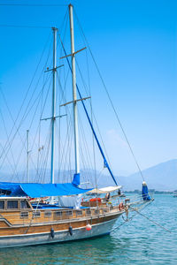 Sailboats moored in sea against clear blue sky