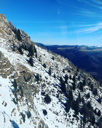 Scenic view of snowcapped mountains against blue sky