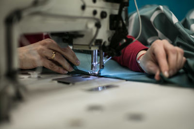 Cropped hands of female tailor using sewing machine