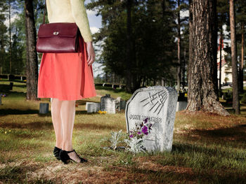 Low section of woman standing by tree on field