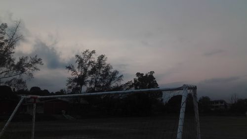 Trees on field against cloudy sky