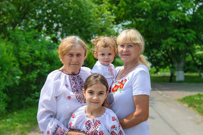 Happy family standing against tree outdoors