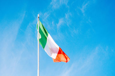 Low angle view of italian flag waving against blue sky