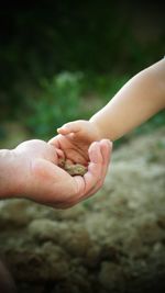 Close-up of hand man giving clay to child