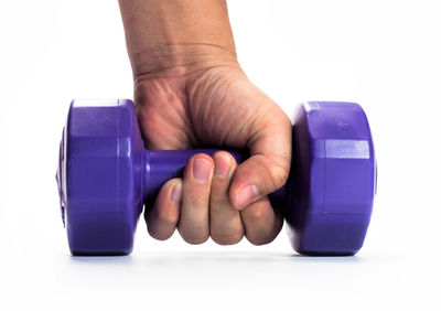 Close-up of hand holding blue glass against white background
