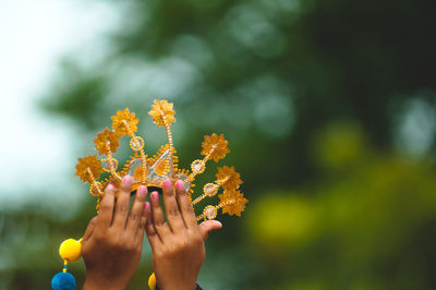 Close-up of hand holding crown against the sky