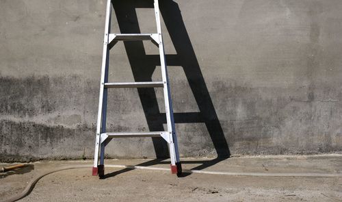 Ladder leaning against grey wall