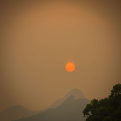 Scenic view of silhouette mountains against orange sky