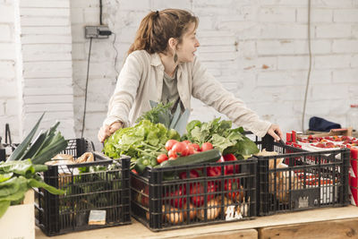 Owner leaning on vegetable crates at checkout counter in shop