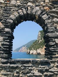 Stone wall by sea against clear sky