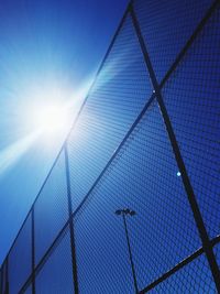 Low angle view of chainlink fence against blue sky