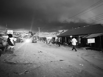 People walking on street amidst buildings at dusk