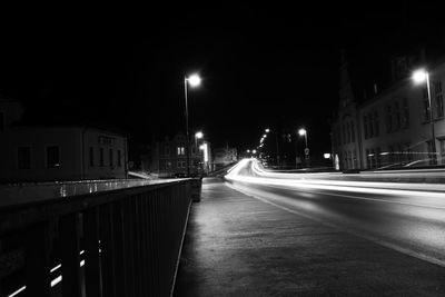 Illuminated street amidst buildings in city at night