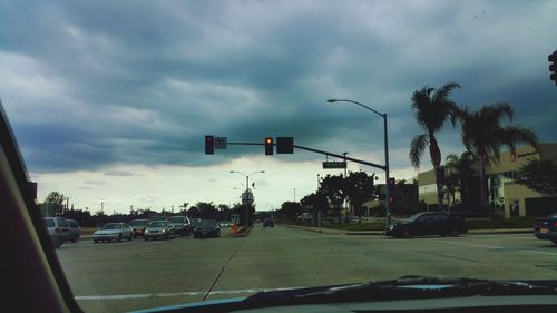 Cars on road against cloudy sky