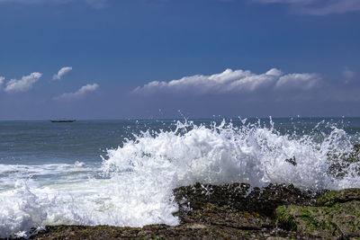 Waves splashing on shore against sky