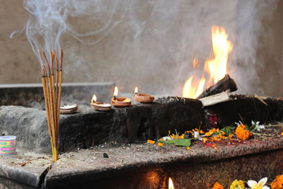 Close-up of incense by lit diyas in temple