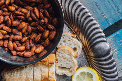 Picnic almonds in silver bowl on silver tray platter with bread, lemon on blue wood 