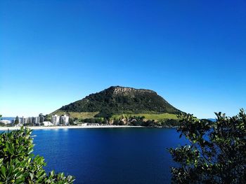 Scenic view of sea and mountains against clear blue sky