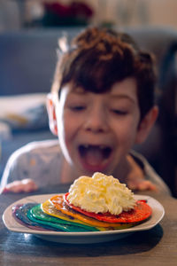 Portrait of boy with pancakes and cream in plate