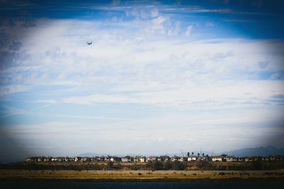 Distant view of city against cloudy sky