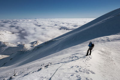 Man on snowcapped mountain against blue sky