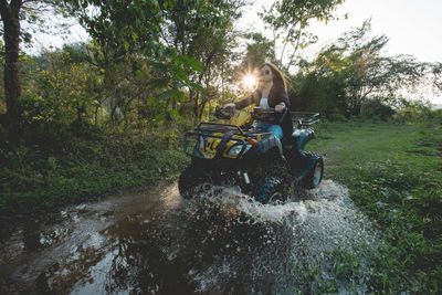 People riding motorcycle on tree by water