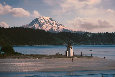 Lighthouse by sea against sky during winter