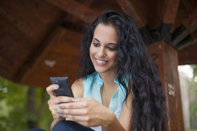 Portrait of smiling young woman using mobile phone outdoors