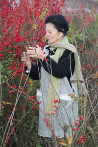 Young woman standing by red flowering plants