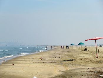 Group of people on beach against clear sky
