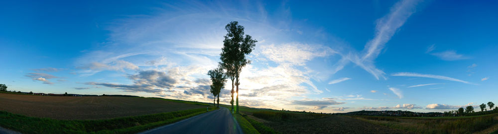 Panoramic view of road amidst field against sky