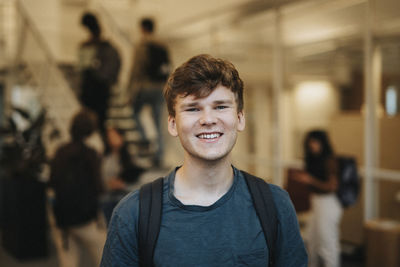 Portrait of cheerful young male student standing in university