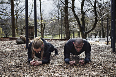 Multi-ethnic couple performing plank exercise at forest